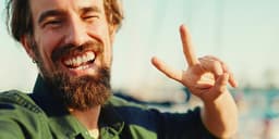 freiheit+ Blog: Deine Inspiration für mehr Freiheit / Lachender Mann zeigt Peace-Zeichen