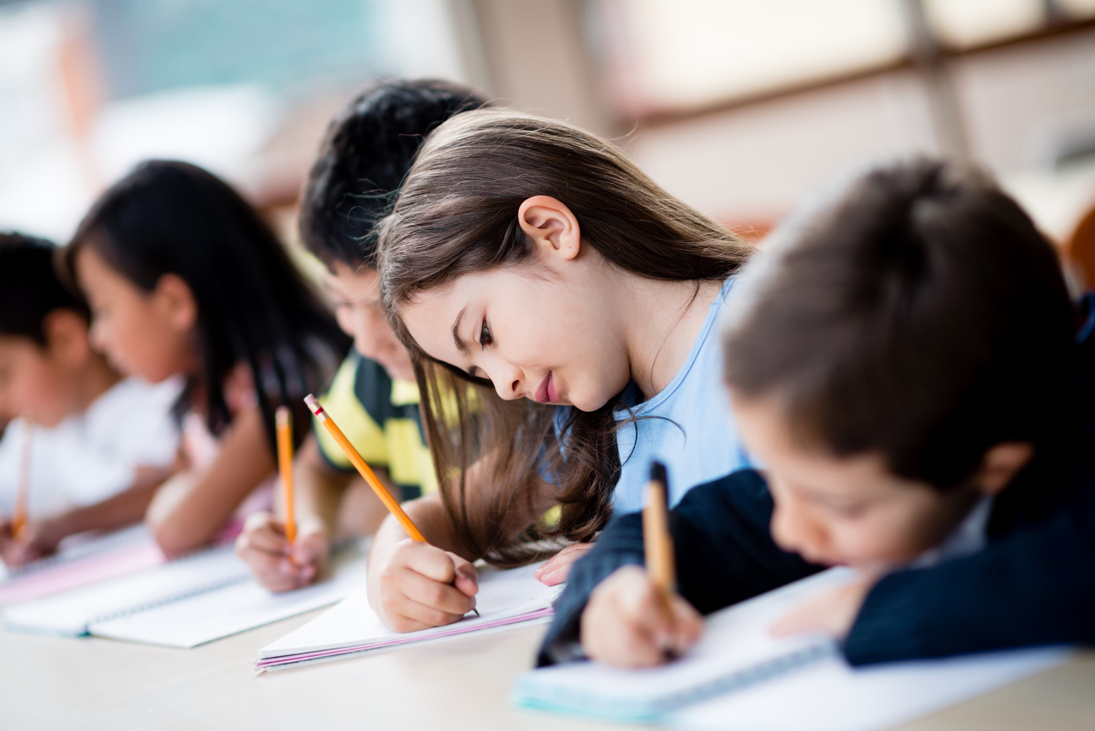 Schüler:innen schreiben konzentriert handschriftliche Texte im Klassenzimmer